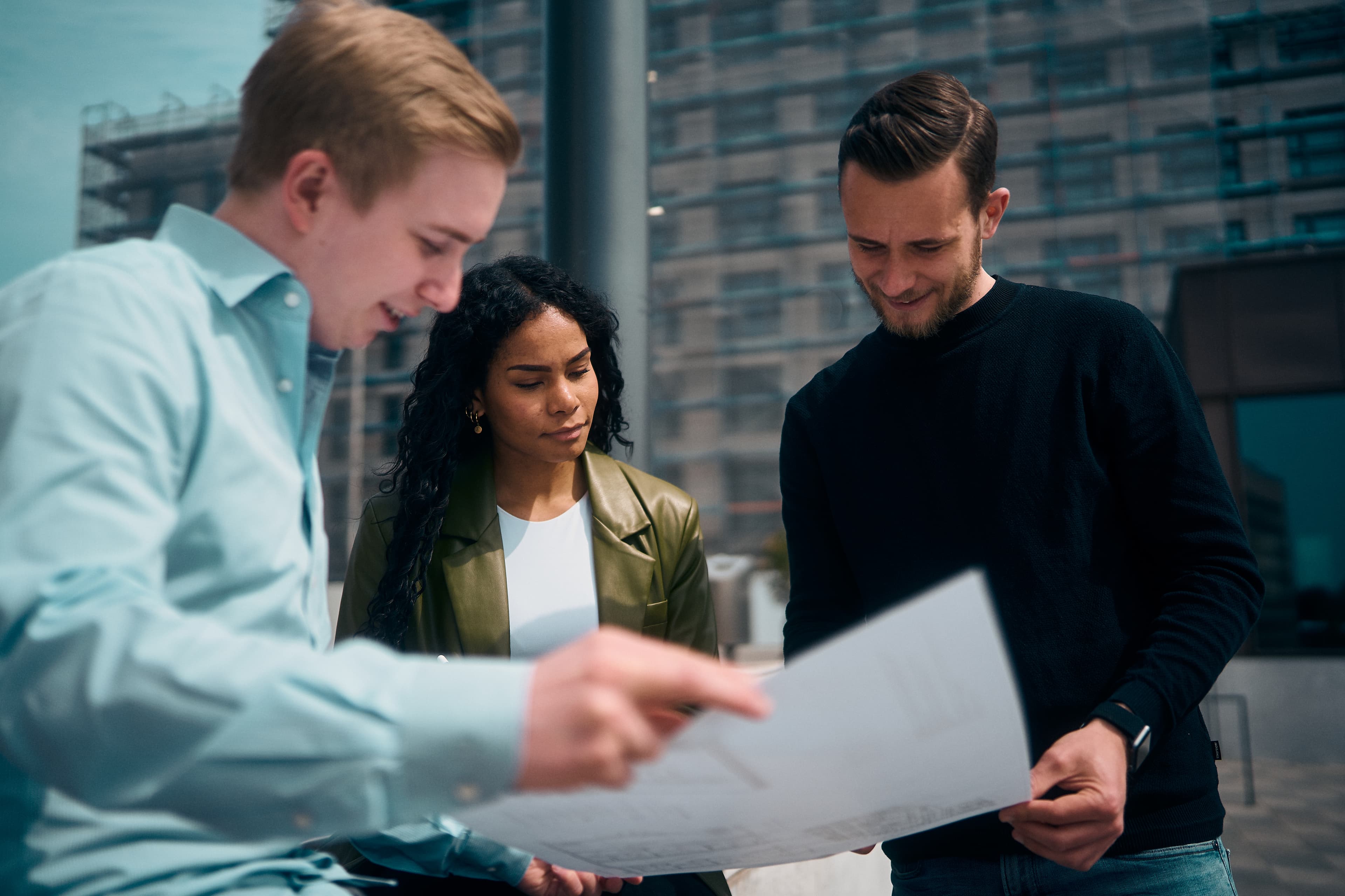 Drei Personen mit großem Bauplan in den Händen